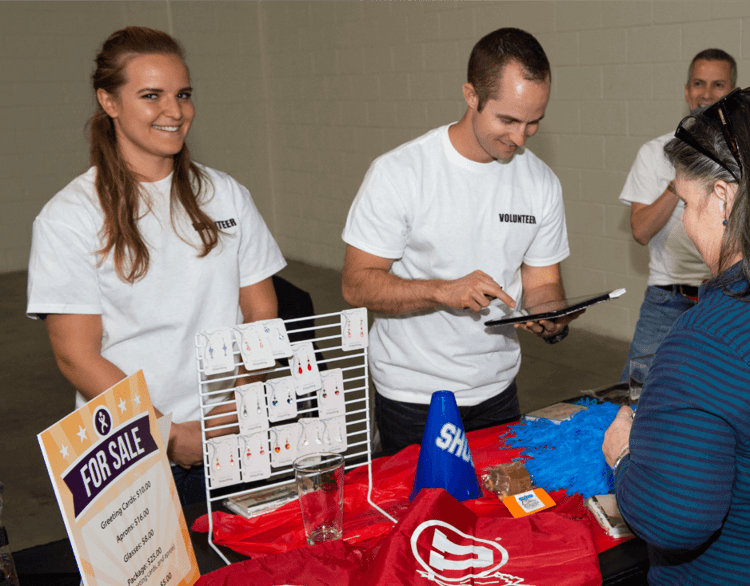 Two volunteers at a Road Home sale table